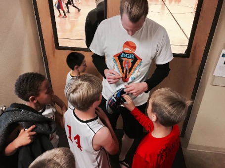 Kyle Singler signing his kid fan shoe by wearing white T-shirt.